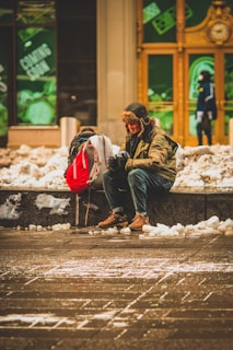 A winter scene with gloves placed next to a wool scarf and hat on a snowy bench.