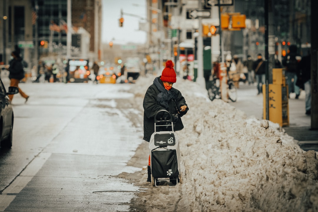 person in black jacket and red knit cap riding black and white motor scooter on road