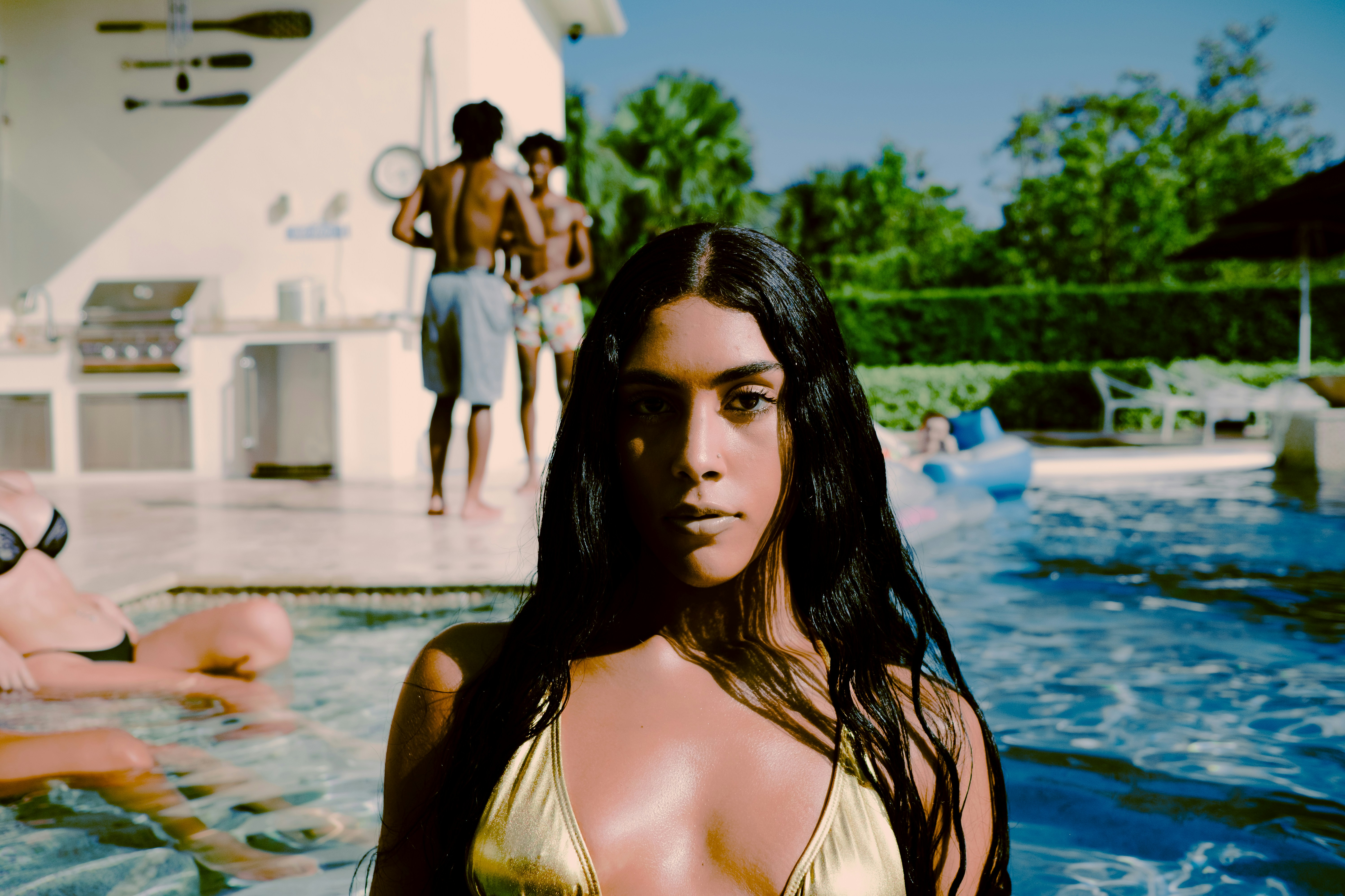 Wanita dengan atasan bikini kuning berdiri di kolam renang di siang hari