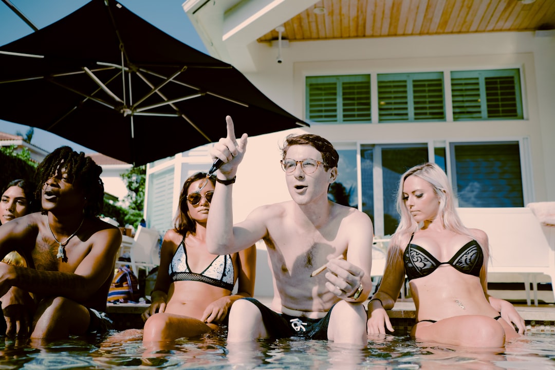 3 women in bikini sitting on water during daytime