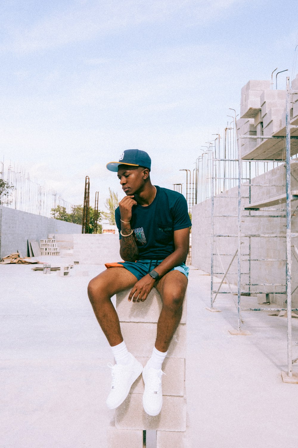 man in black crew neck t-shirt and blue denim shorts sitting on white sand during