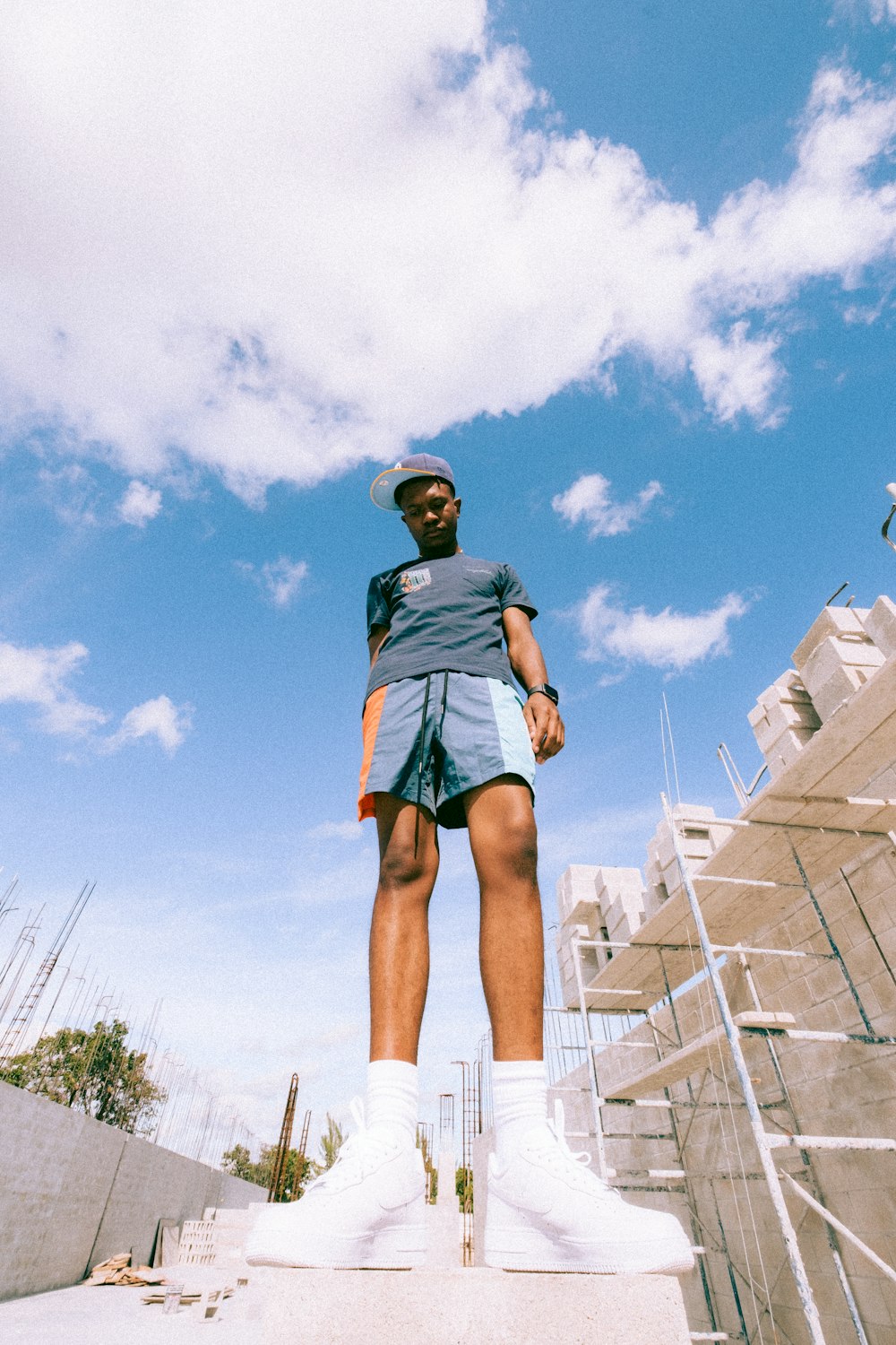 Femme en T-shirt noir et short noir debout sur un bâtiment en béton blanc pendant la journée