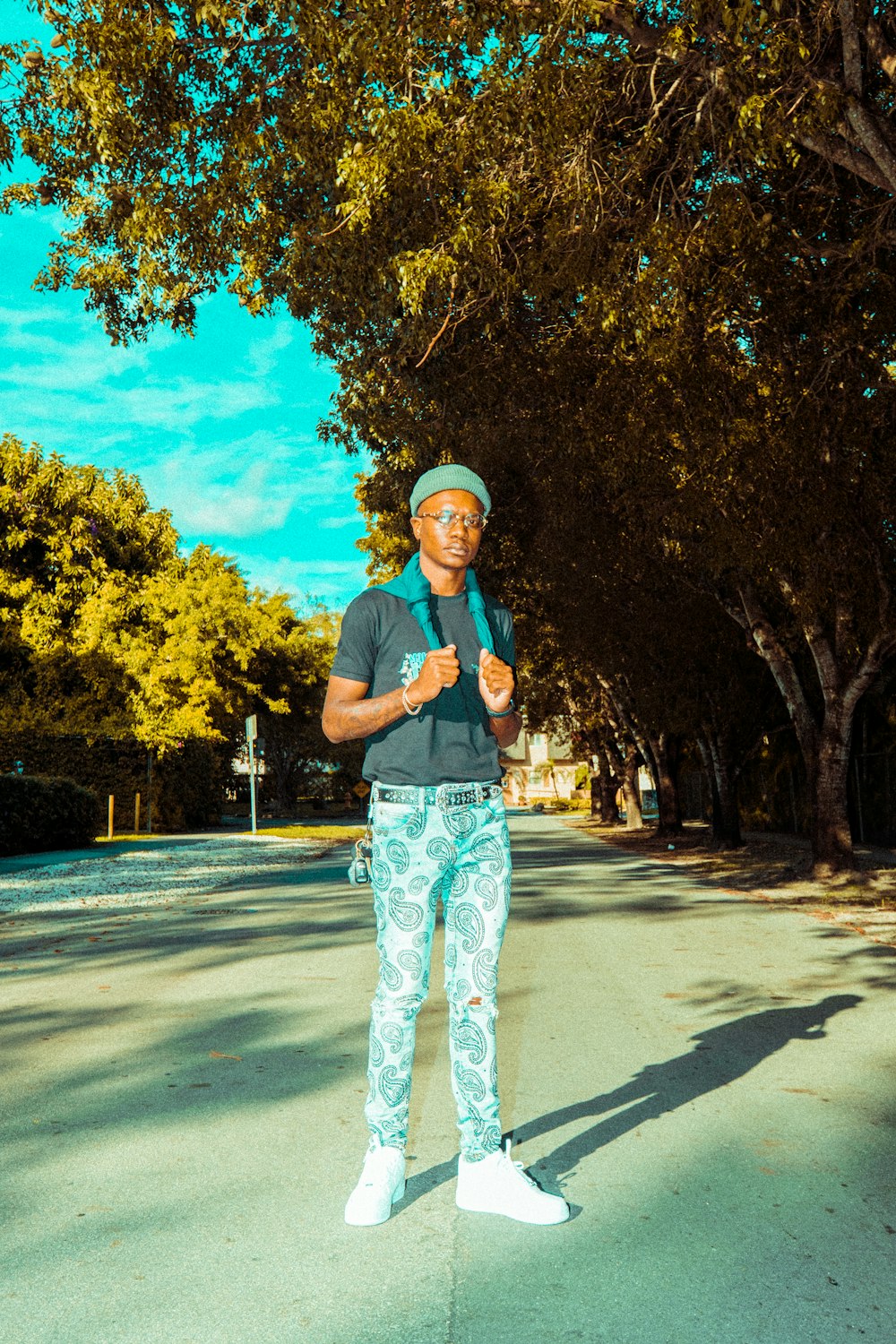 man in black crew neck t-shirt and white pants standing on gray asphalt road during