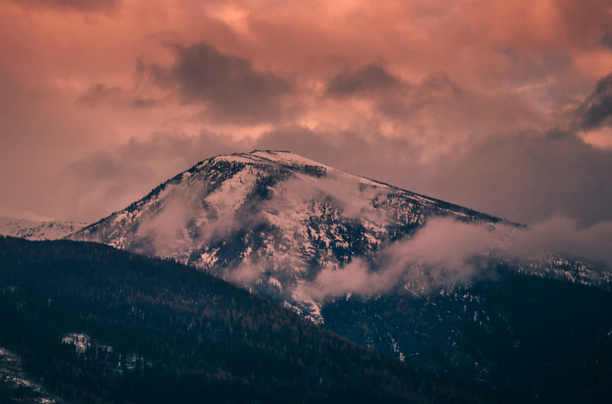 Snow-covered mountain slopes beneath pink clouds in the Missoula area