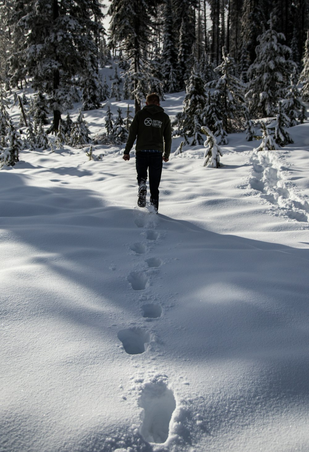 man in black jacket and black pants walking on snow covered ground during daytime