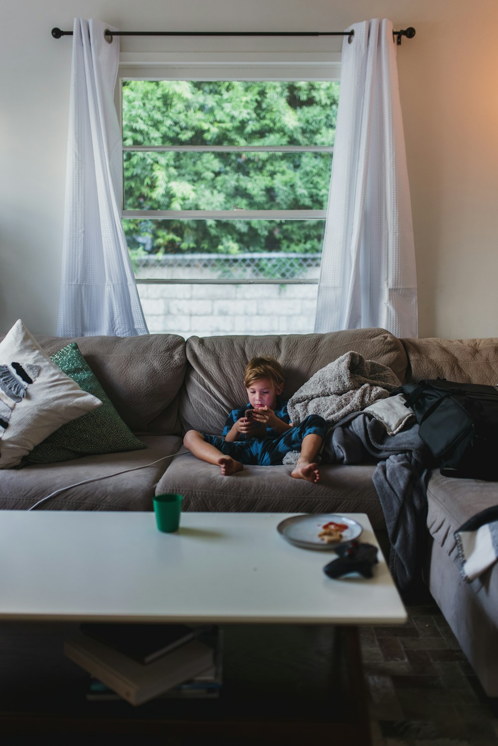 boy in blue shirt lying on gray couch