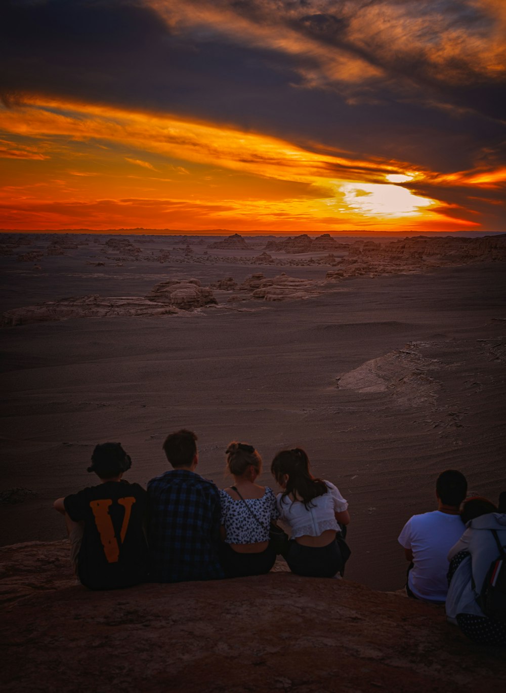 3 men sitting on seashore during sunset