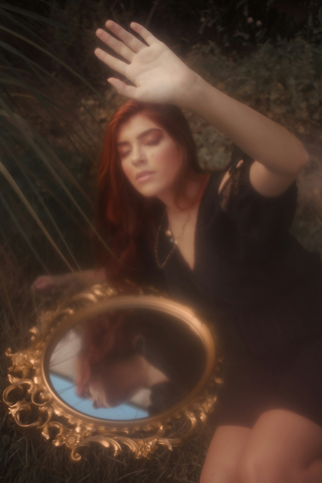 woman in black shirt holding round mirror