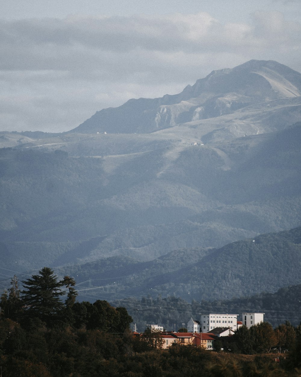 white and brown concrete buildings near green trees and mountains during daytime