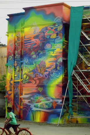 An artist painting a lively mural inspired by coral reefs and cultural symbols under warm natural light.