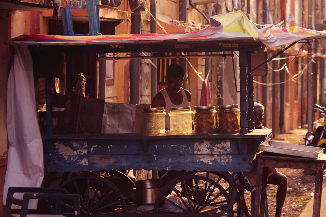 man in white shirt sitting on black wooden cart, Local Tea & Coffee Vendor at the streets of Chennai.