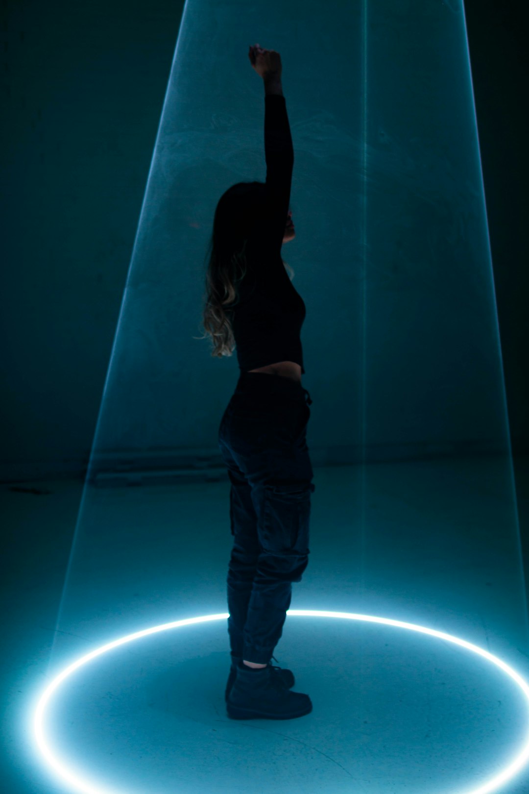 woman in black tank top and blue denim jeans standing on blue light