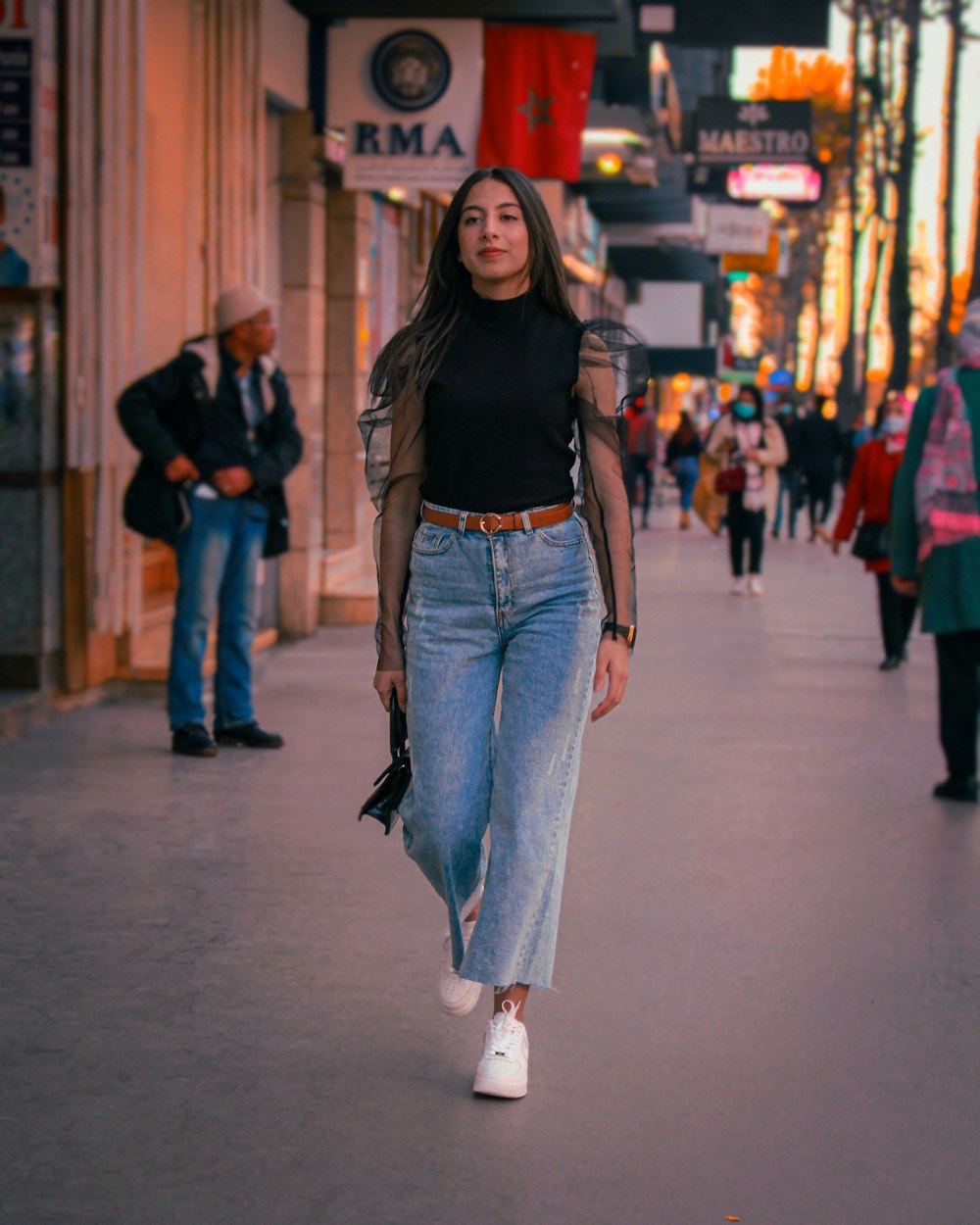 woman in black shirt and blue denim jeans standing on street during daytime