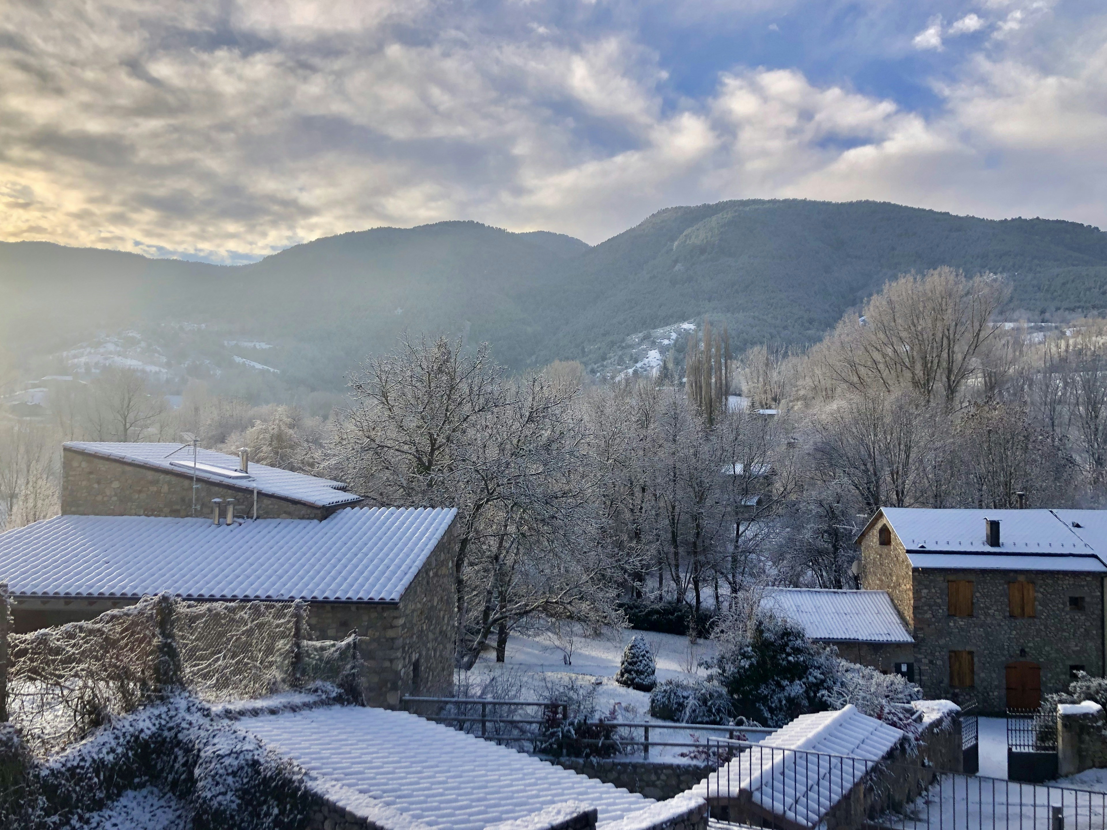 brown and white house near trees and mountains under white clouds and blue sky during daytime
