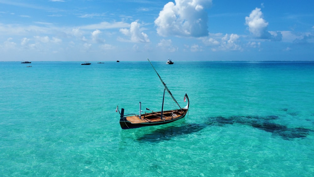 brown boat on blue sea under blue sky and white clouds during daytime