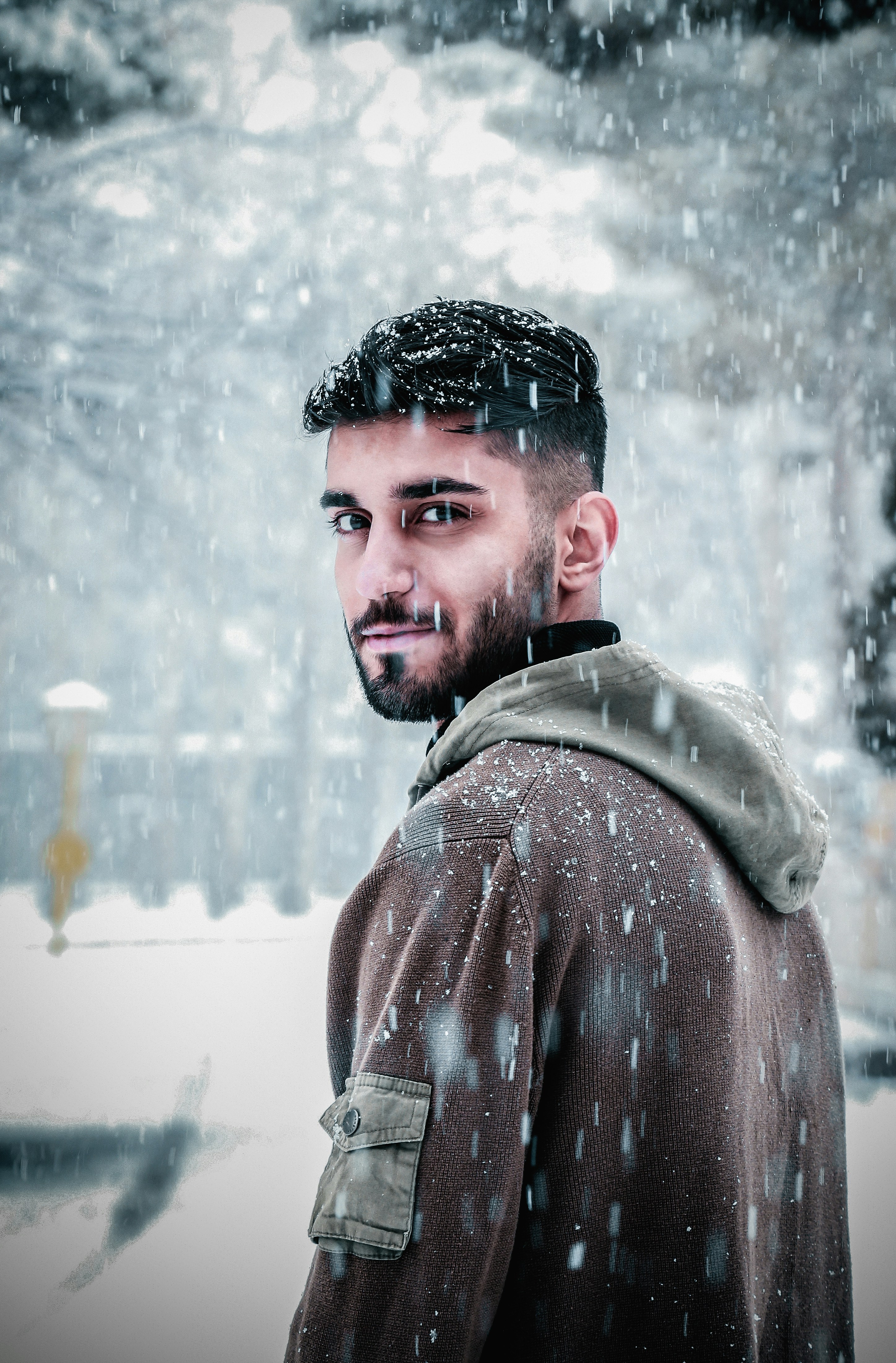 man in brown jacket standing on snow covered field during daytime