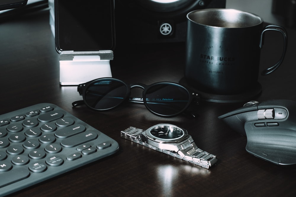 black framed sunglasses beside black ceramic mug