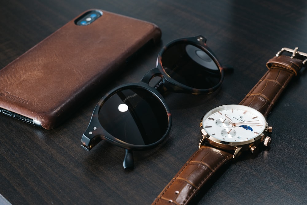 black framed sunglasses beside brown leather case