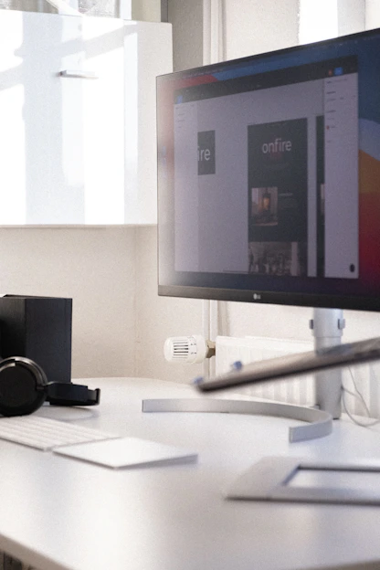 A sleek workspace featuring a high-resolution monitor displaying a minimalistic digital product design.