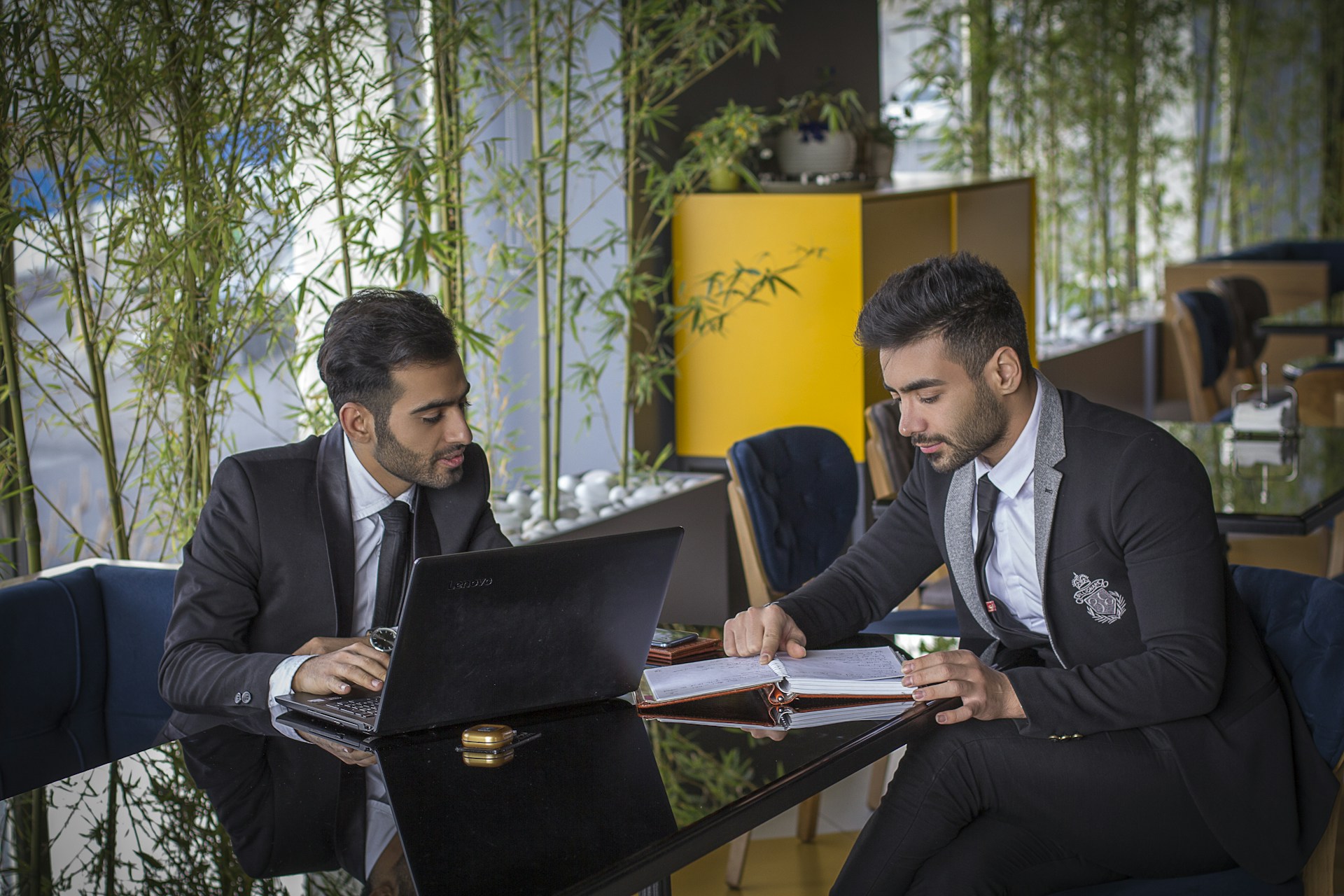 man in black suit jacket sitting beside man in black suit