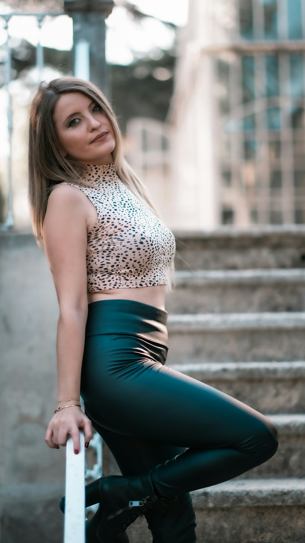 woman in black and white leopard print tank top and blue leggings sitting on concrete stairs