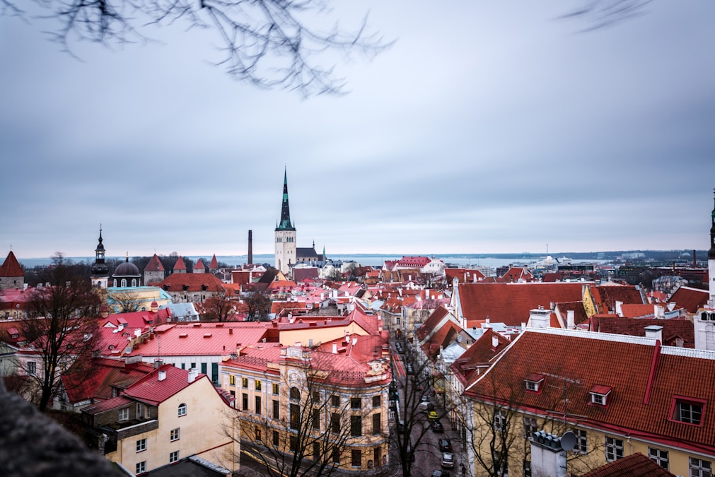 Aerial view of Tallinn's medieval old town with red rooftops and church spires under a moody sky