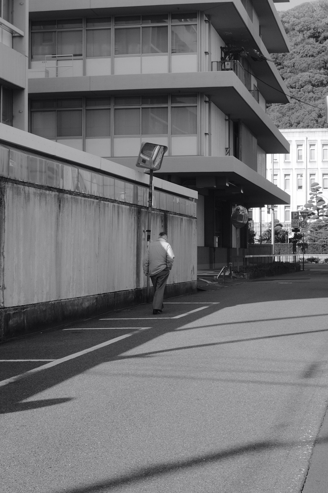 grayscale photo of man walking on sidewalk