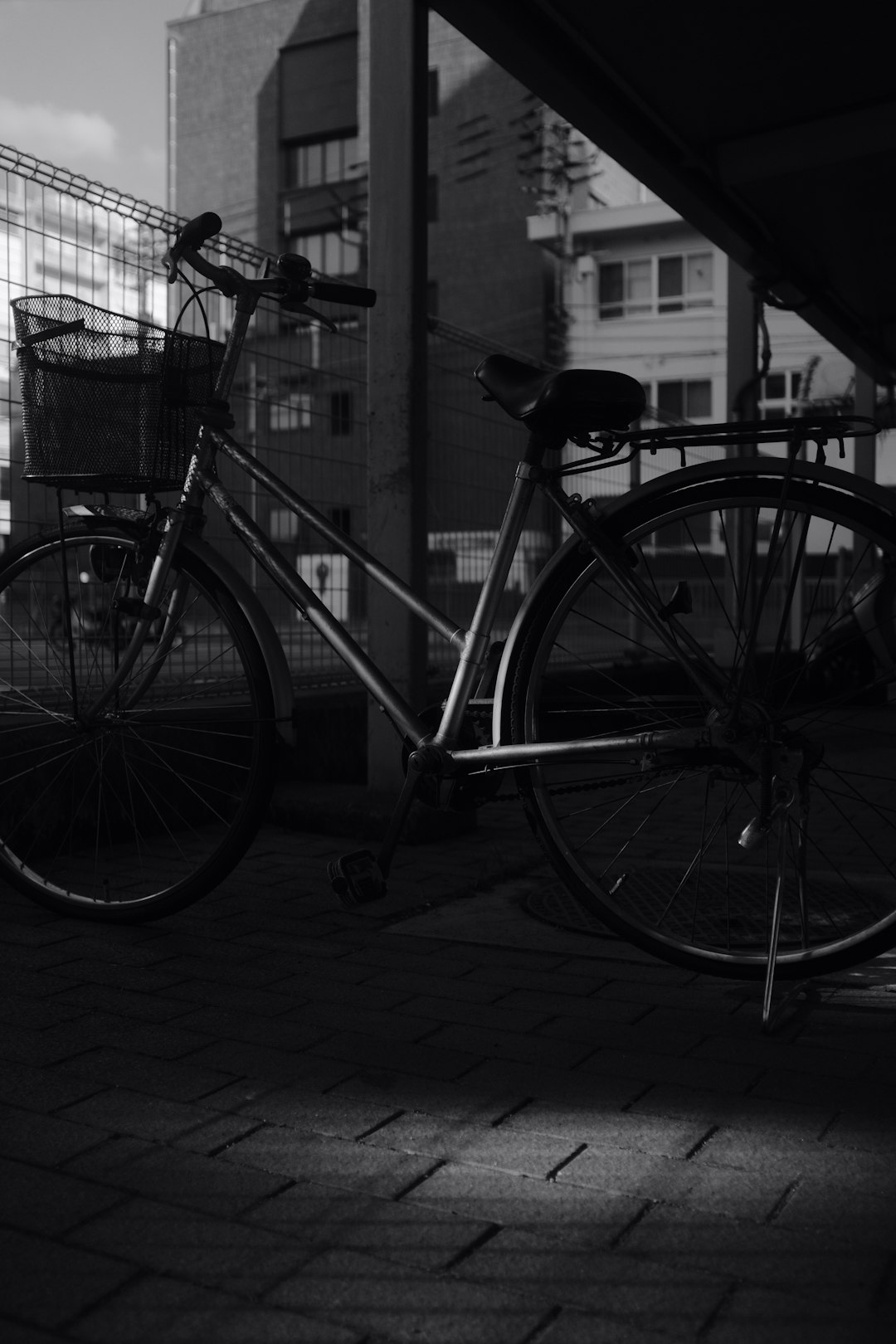 grayscale photo of city bicycle parked beside metal fence