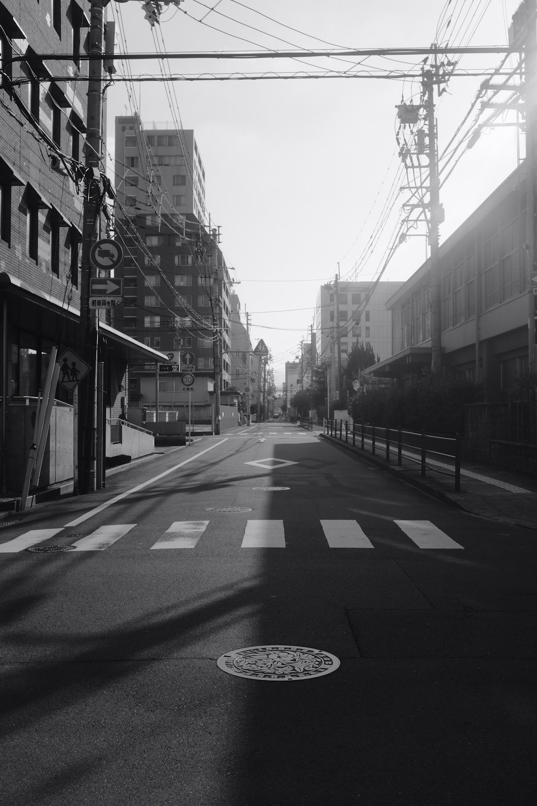 grayscale photo of empty road between buildings