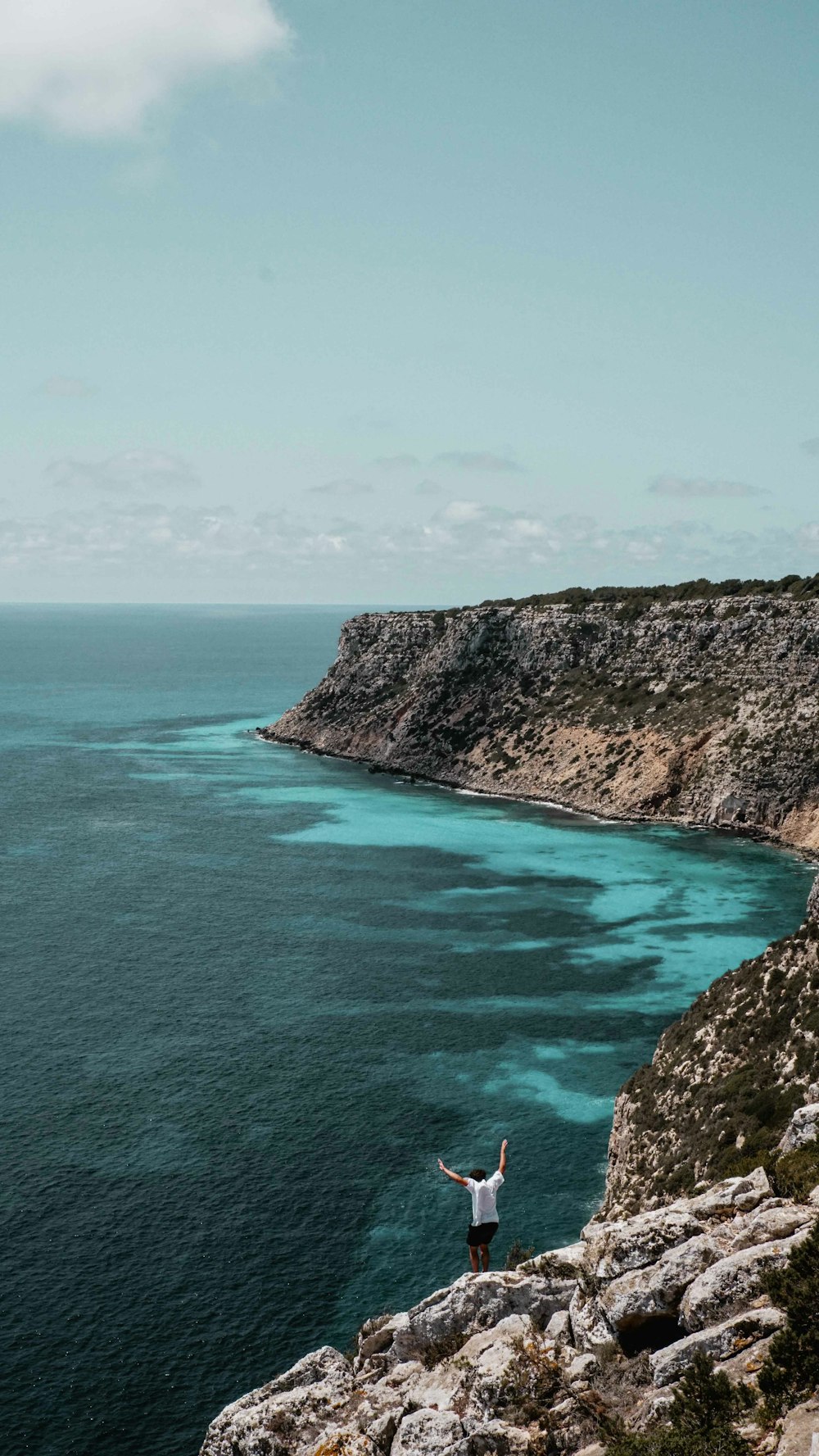 brown and green mountain beside blue sea under blue sky during daytime