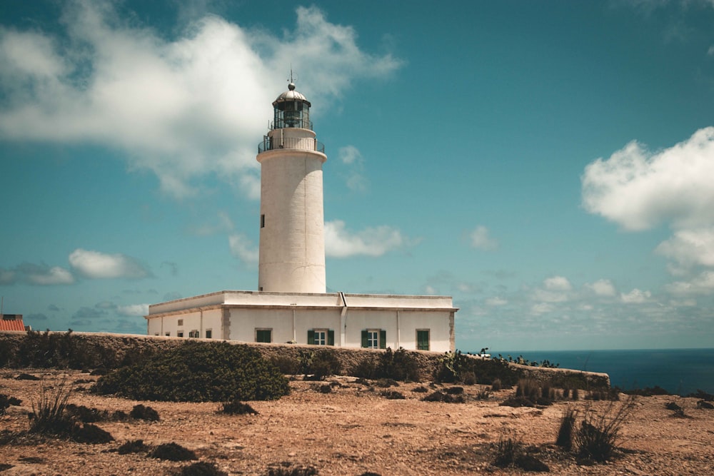 farol branco e preto sob o céu azul durante o dia