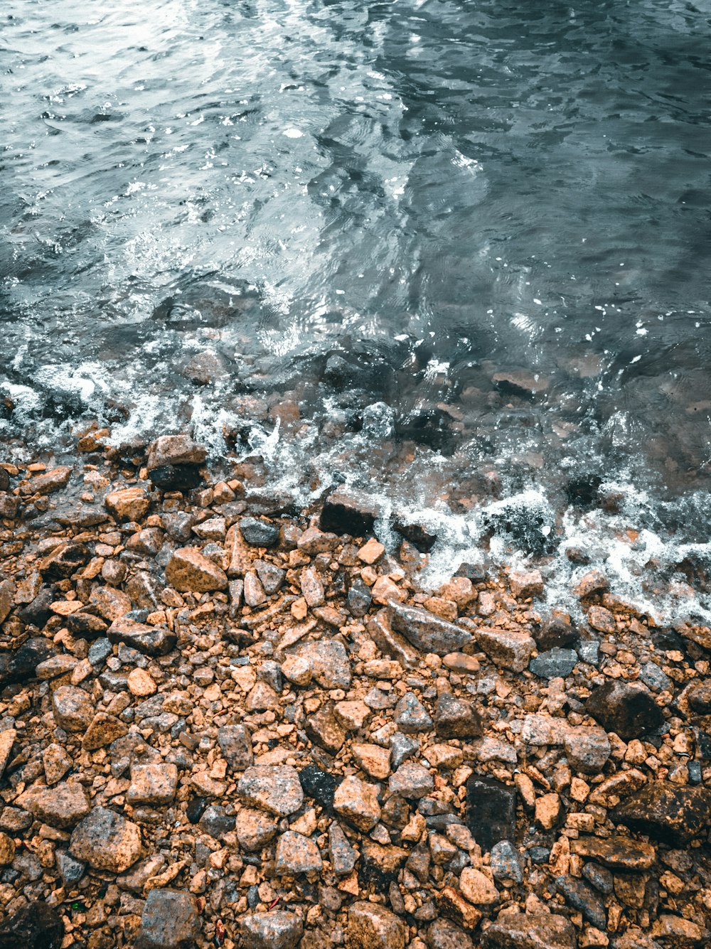 brown and black stones near body of water