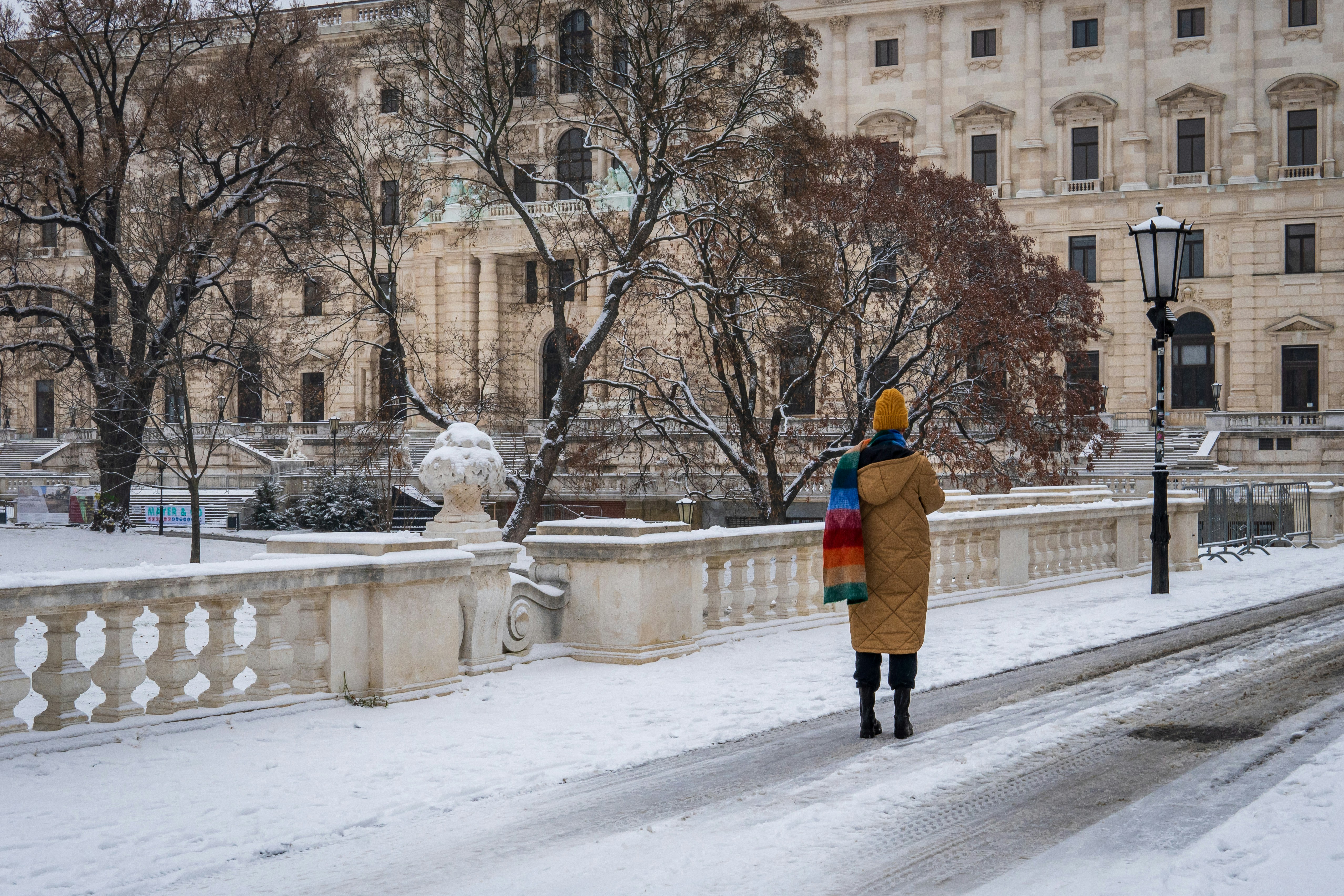 personne en veste bleue et jaune marchant sur une route enneigée pendant la journée