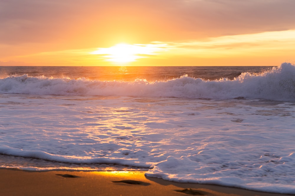 ocean waves crashing on shore during sunset