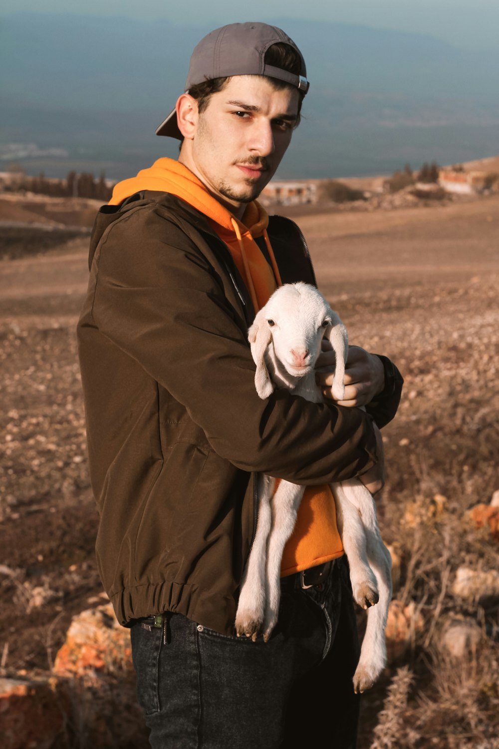 man in brown jacket hugging white and gray penguin