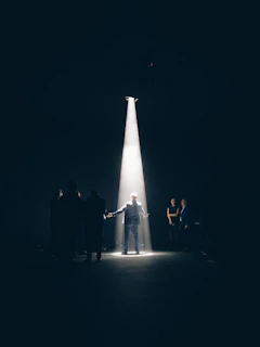 A dramatic stage scene with Michael Disanka performing under warm spotlight in an intimate theater setting.