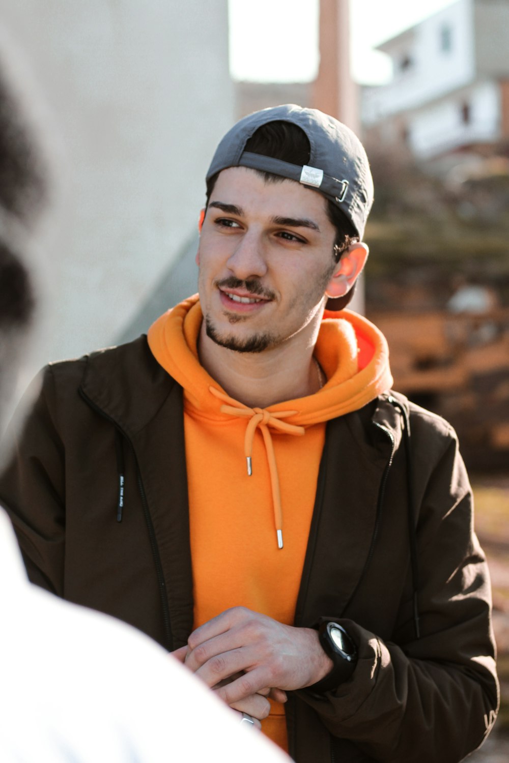 homem em jaqueta de zíper preto e laranja sorrindo