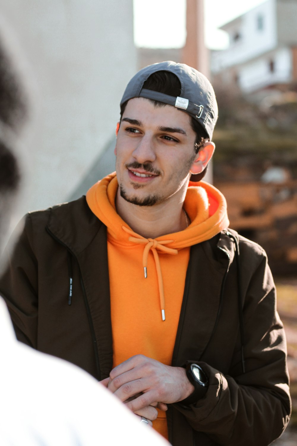 man in black and orange zip up jacket smiling