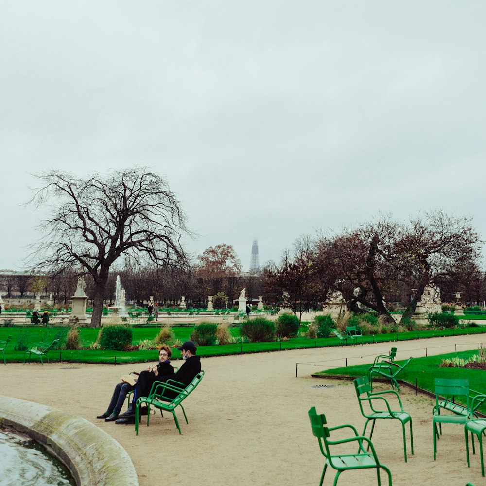 green metal chairs on green grass field near trees during daytime