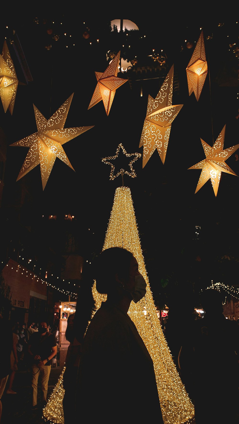 woman in black long sleeve shirt standing beside lighted star decor during night time