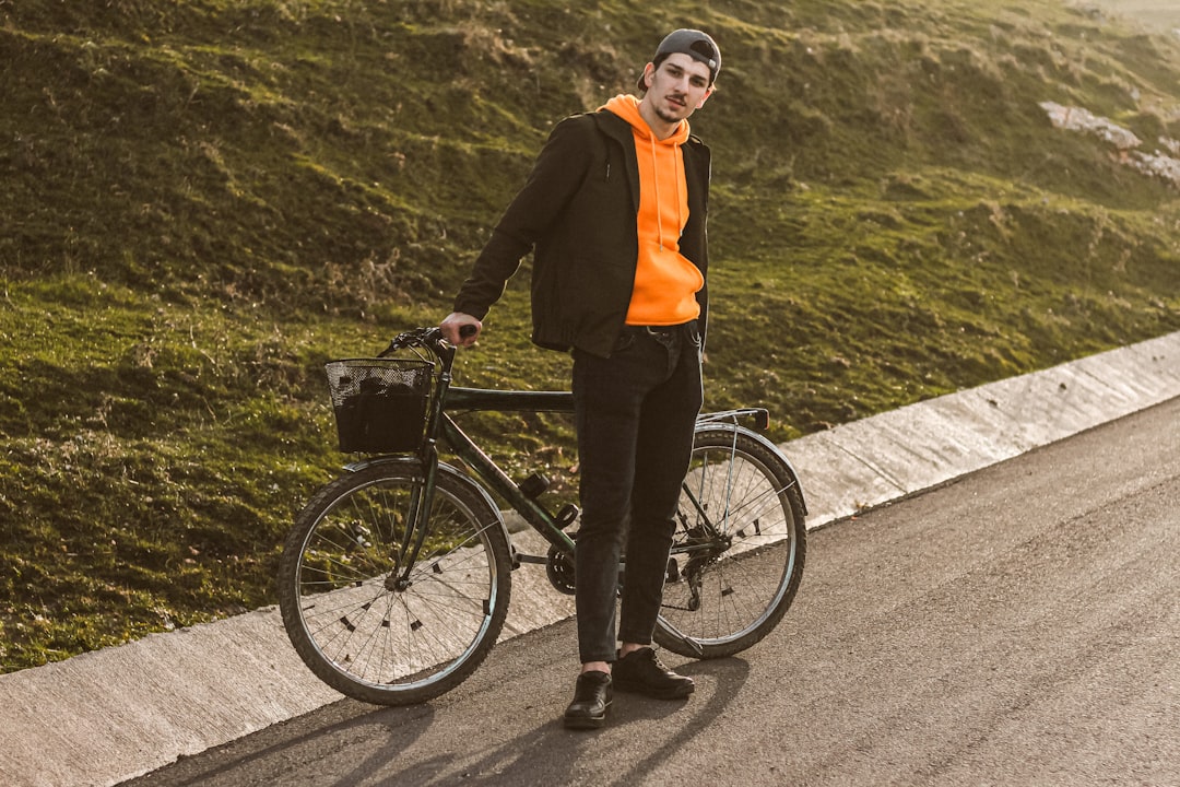 woman in black jacket and black pants riding on black bicycle on gray concrete road during