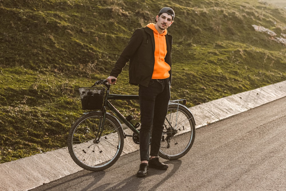 Mujer en chaqueta negra y pantalones negros montando en bicicleta negra en carretera de concreto gris durante