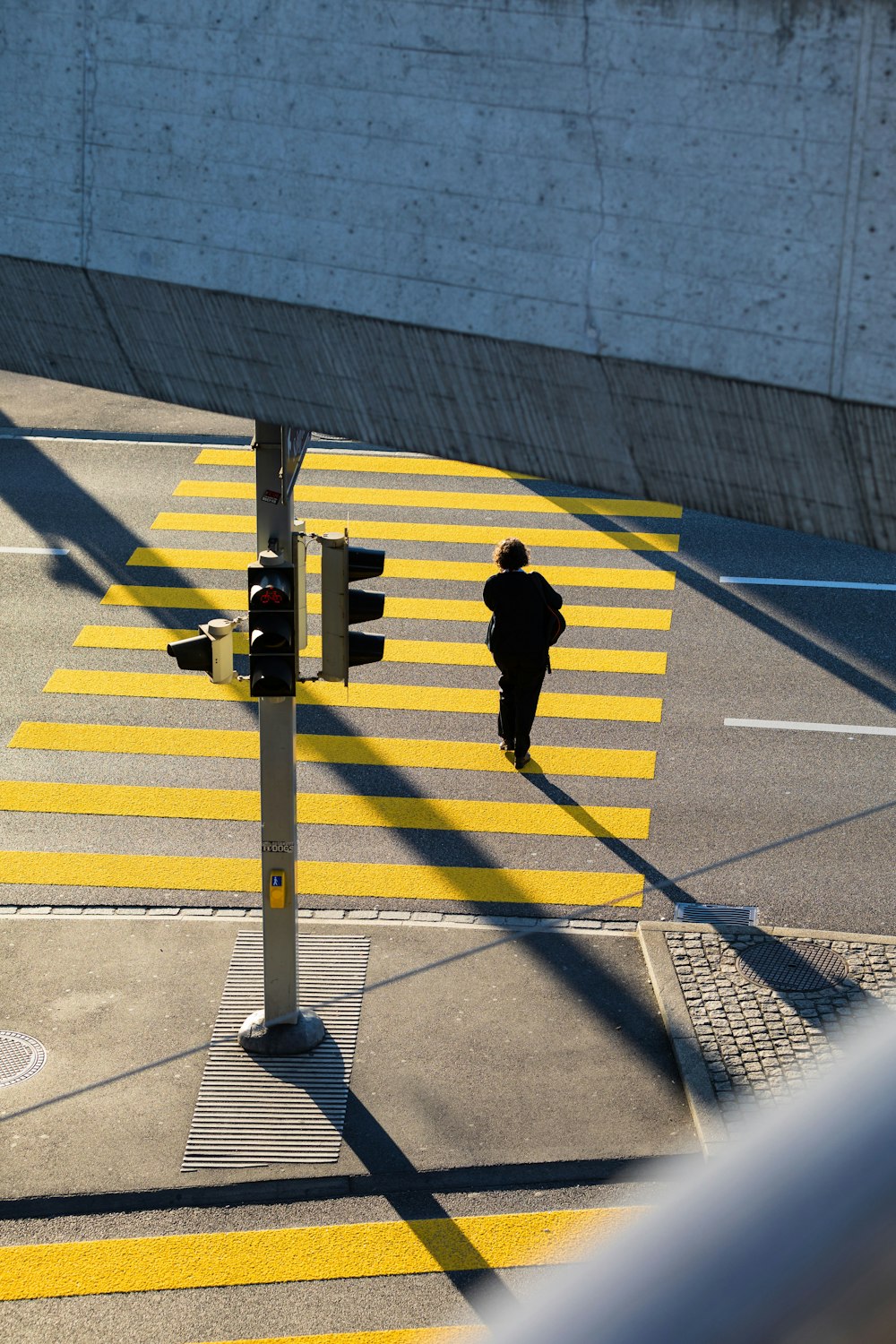man in black jacket and pants walking on pedestrian lane during daytime