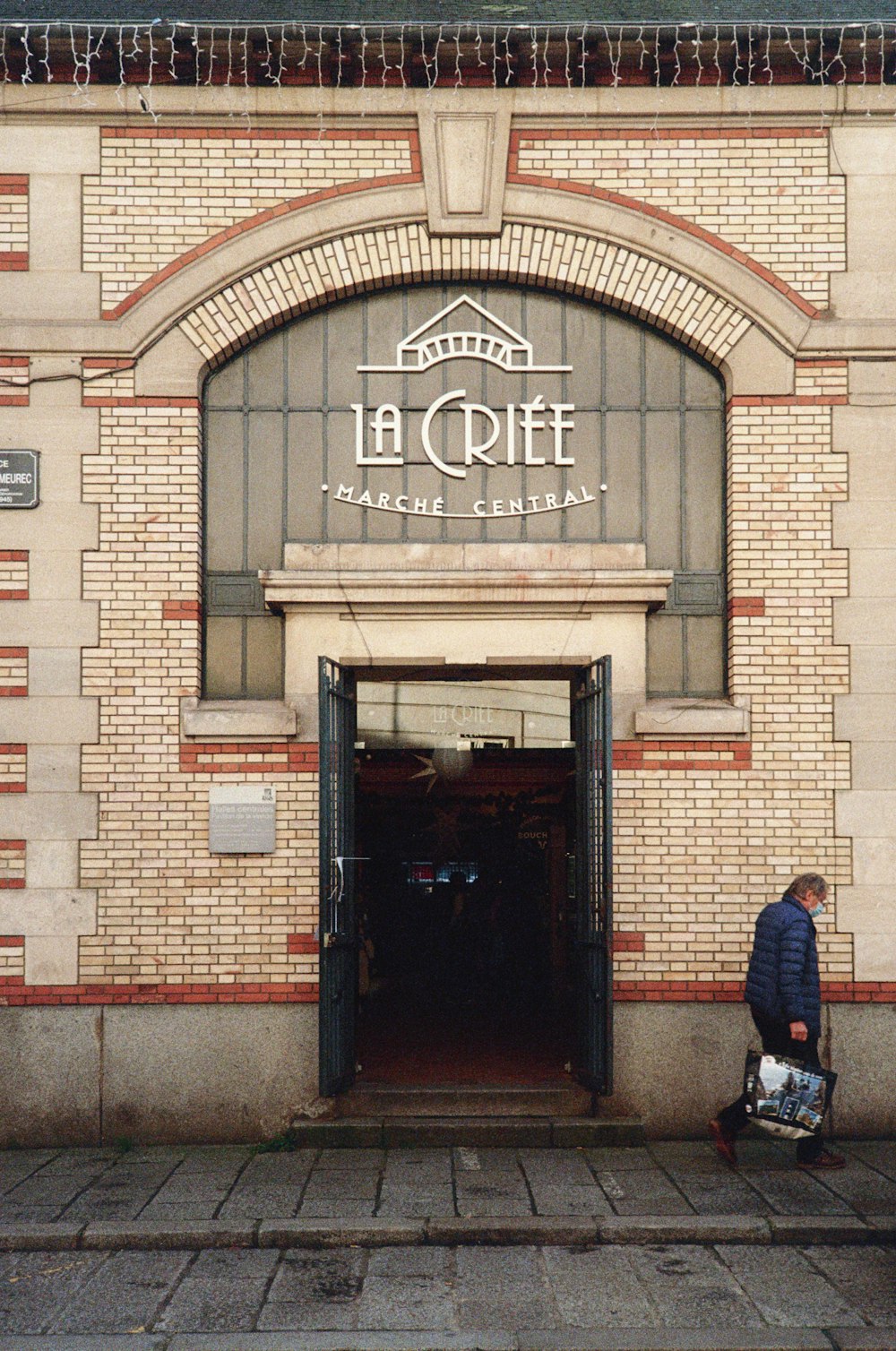 man in blue jacket standing in front of brown brick building