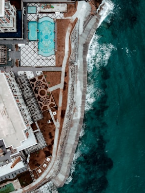 Aerial shot of a luxury property complex near the sparkling ocean coastline