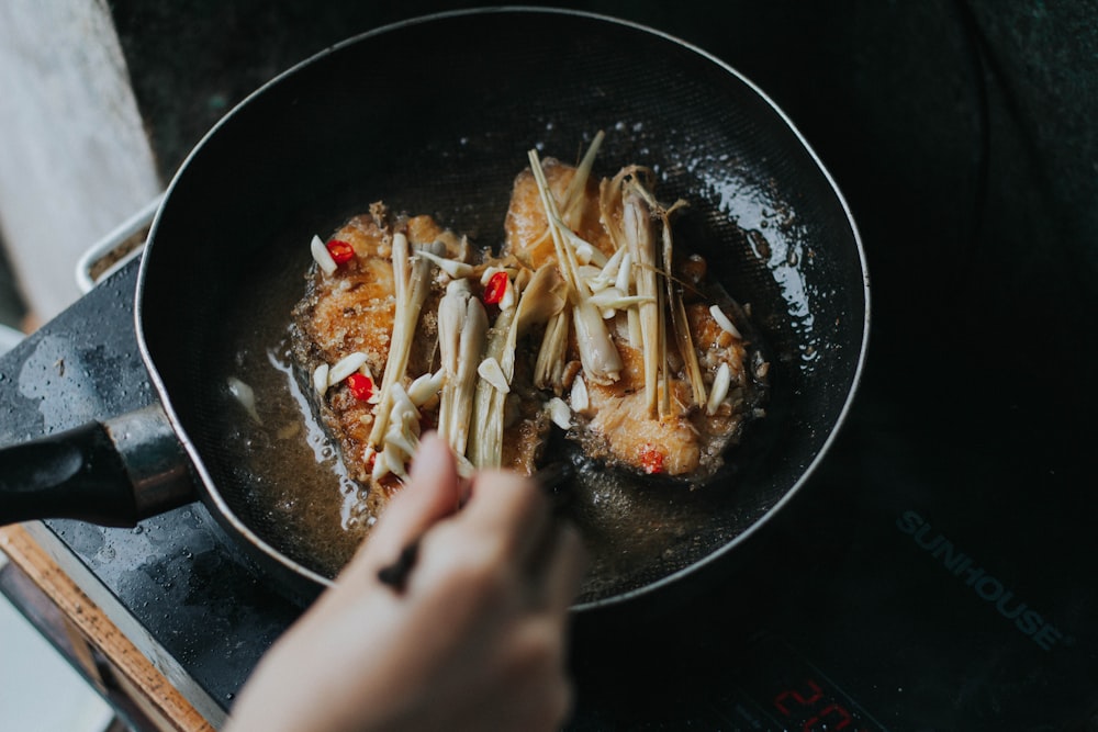 person holding black ceramic bowl with food