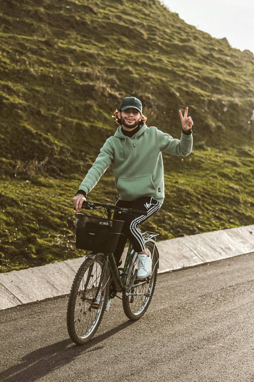 낮 동안 도로에서 자전거를 타는 녹색 까마귀를 입은 남자