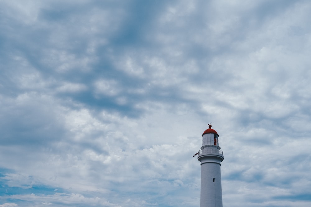 white and red lighthouse under cloudy sky during daytime