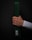 A hand holds a green martial arts belt against a dark background. The belt displays a patch with the word 'BLITZ' in white letters. The hand is clenched around the folded belt, showing visible veins and a light skin tone. The person is wearing a white long-sleeved garment.