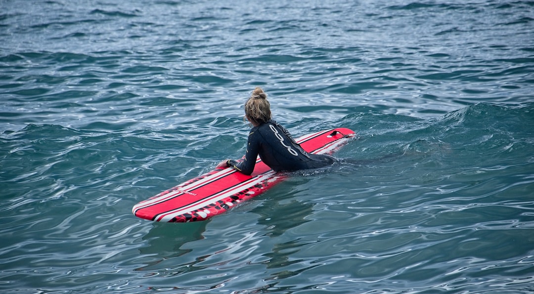 woman in black jacket riding red and white kayak on body of water during daytime